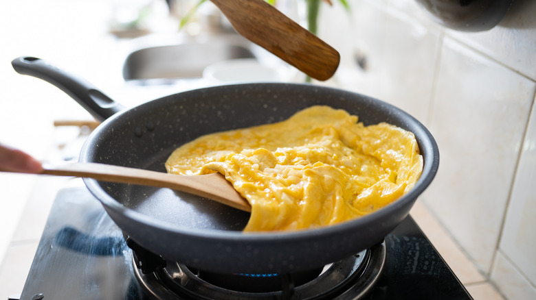 Lifting omelet in pan with wooden spatula