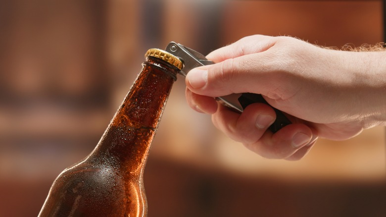hand opening beer bottle