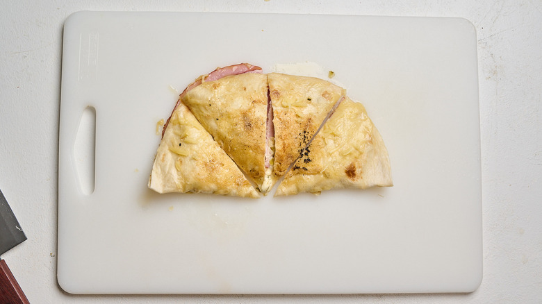 quesadilla sliced into quarters on a cutting board
