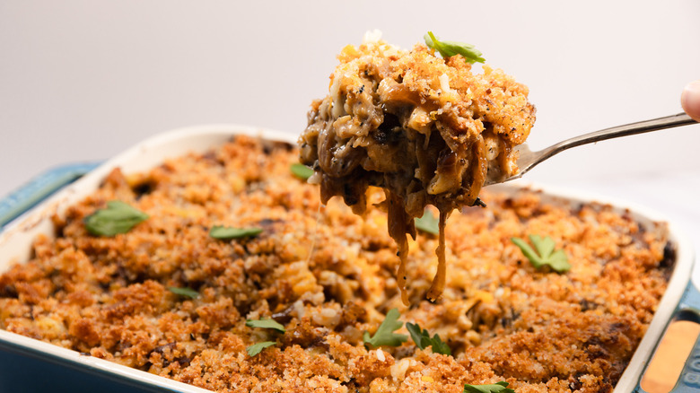 Lifting a serving of French onion mac and cheese from a casserole dish
