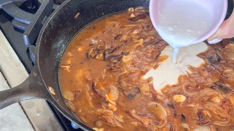 Cream pouring into brothy onion mixture in skillet