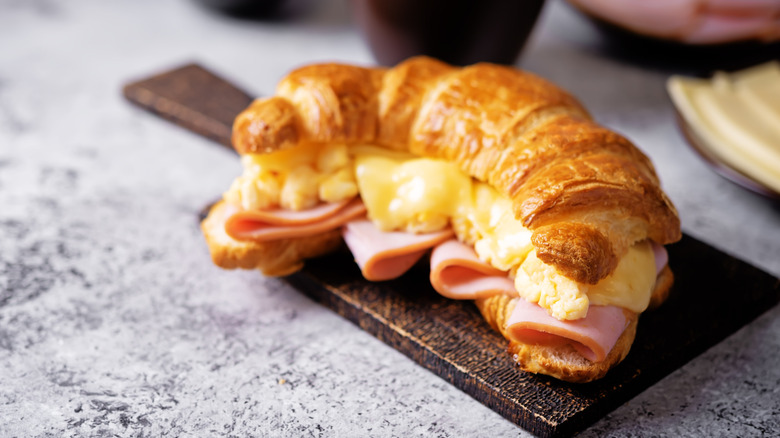A ham and egg filled croissant on a serving board