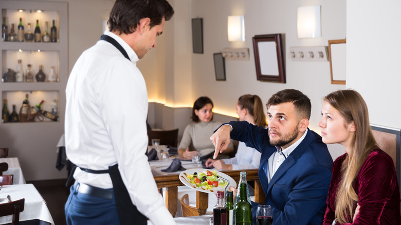 Unhappy customers in a restaurant complaining about food to a waiter