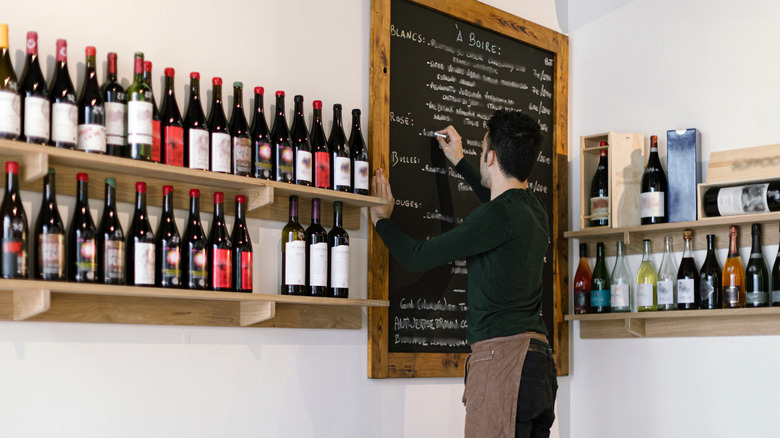 A waiter writing a wine list on a chalkboard