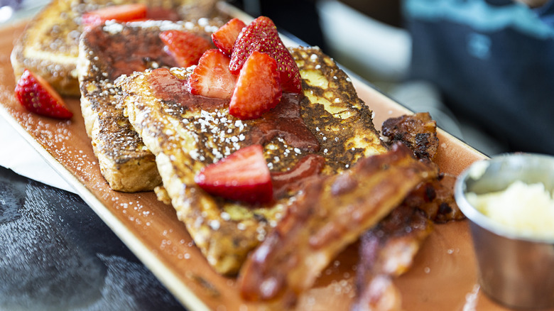 Plated French toast, with berries and powdered sugar