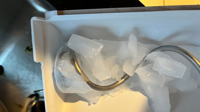 An automatic ice maker in a Whirlpool freezer that is frozen over and no longer producing ice