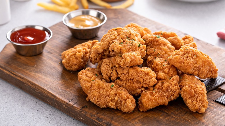 Fried chicken tenders and sauces on board