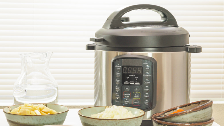 An Instant Pot sitting on a kitchen counter next to bowls of food