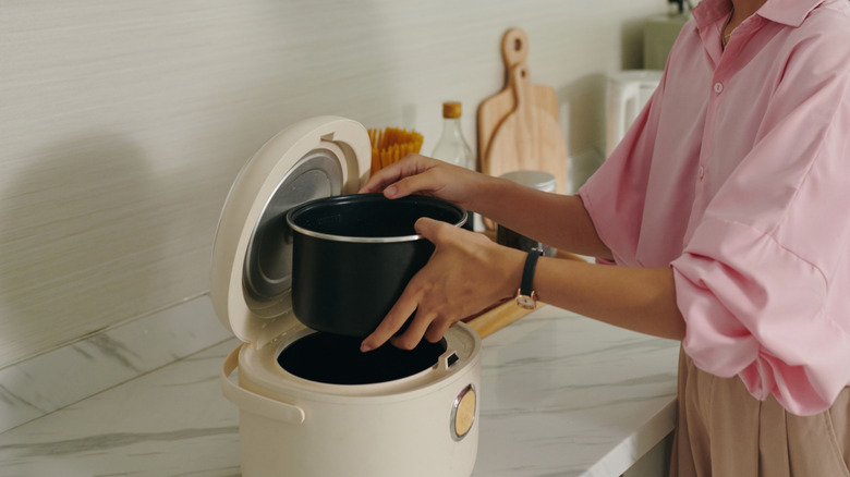 A woman checking the water level inside a pressure cooker