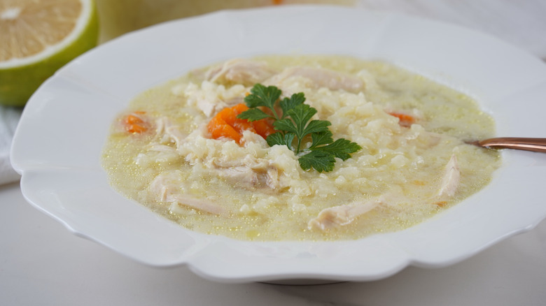 a bowl of Greek avgolemono soup garnished with carrot and parsley