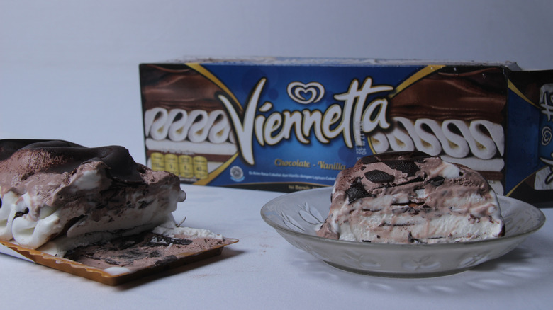 A box of Good Humor Viennetta ice cream cake next to the cake and a glass bowl holding a slice of the cake