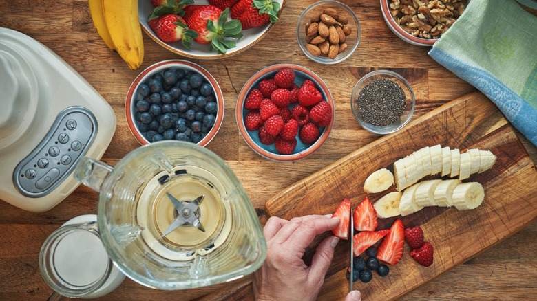 blender on a wooden table full of fresh fruit