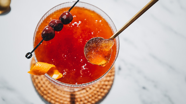 Lifting a spoon from a frozen Manhattan cocktail.