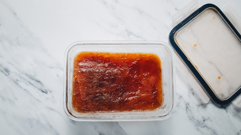 A glass container with the frozen mixture of a Manhattan cocktail.