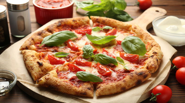 margherita pizza on wood board with tomatoes and sauce