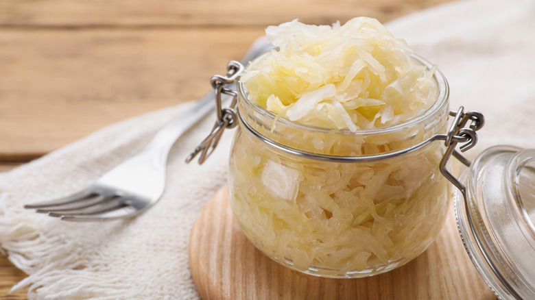 open jar of sauerkraut on wooden board