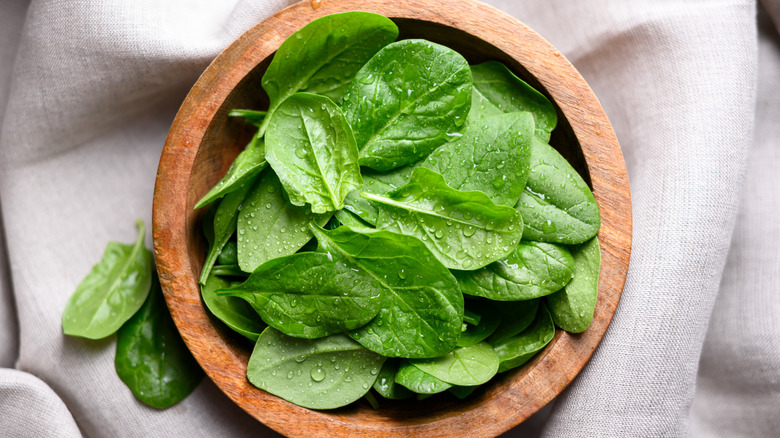 fresh spinach leaves in wooden bowl