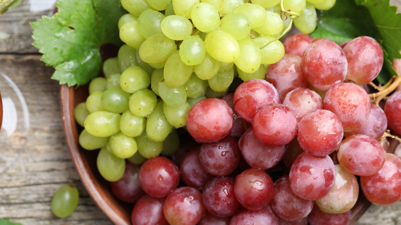 a bowl with a bunch of green grapes and a bunch of red grapes