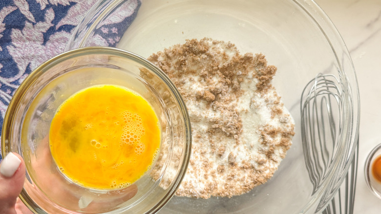 hand adding eggs to bowl