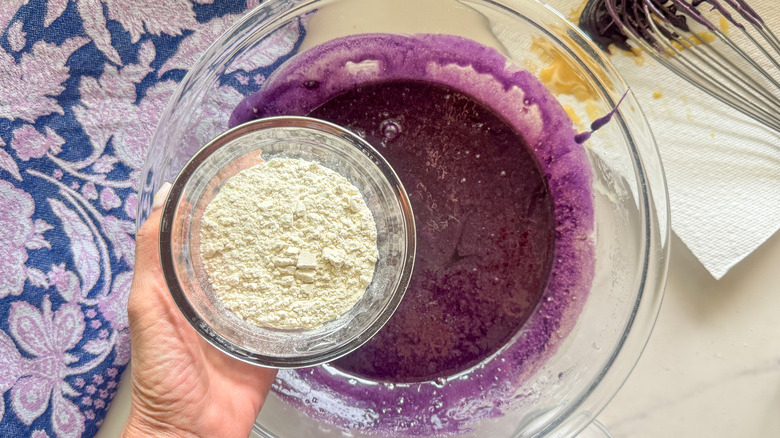 hand adding flour to bowl