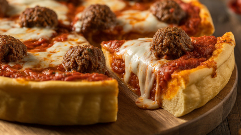 A close up of a Chicago-style deep dish pizza with a slice being pulled out