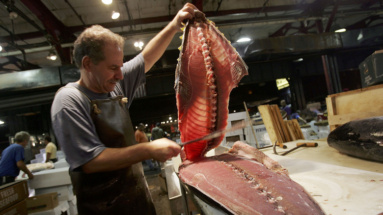 A worker fillets a large fish