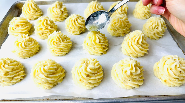Spoon pouring melted butter over potato rosette
