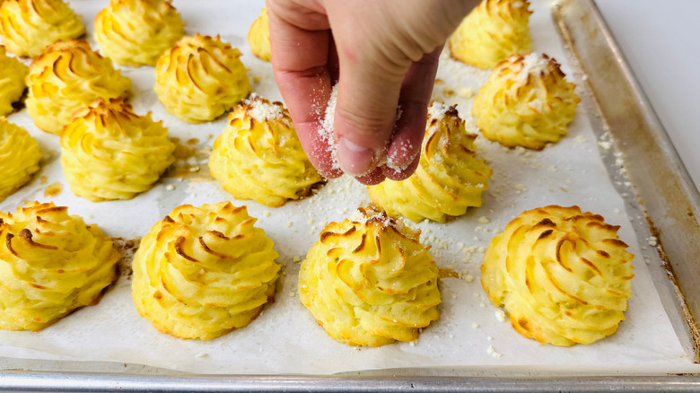 Hand sprinkling parmesan onto duchess potatoes