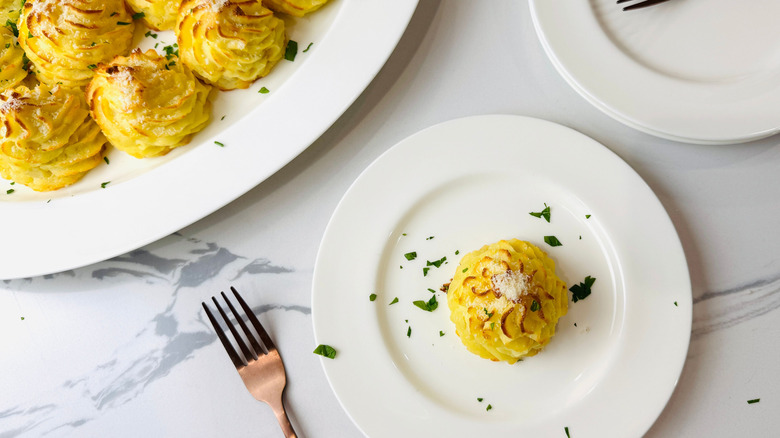 Duchess potatoes on serving platter with one on plate