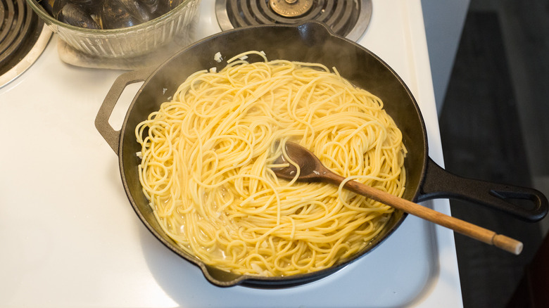 spaghetti cooking in iron pan