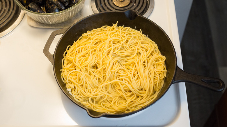 spaghetti cooking in iron pan