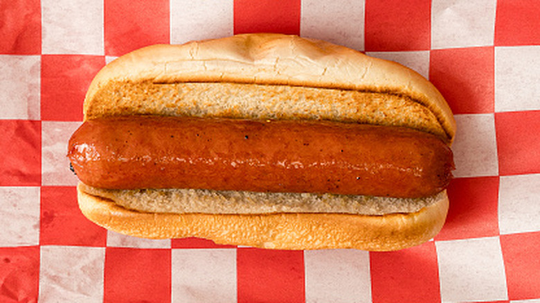 Hot dog in a bun on a red and white checkered paper