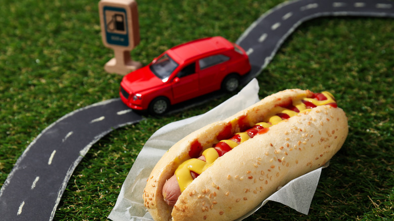 Hot dog on paper with toy car, road, and gas pump