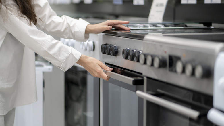 A person opens the door of a stove at a store