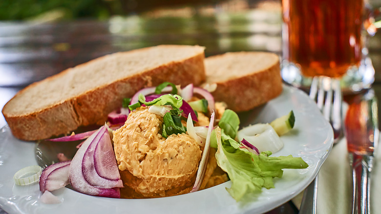 Obatzda served with vegetables and bread, on a table alongside beer