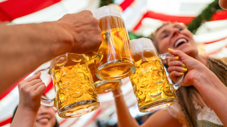 Four friends clinking glasses of beer in a tent