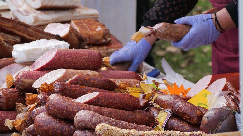 Gloved vendor hands serving sausages at market