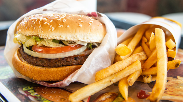 Close up of Burger King Whopper with toppings and fries.