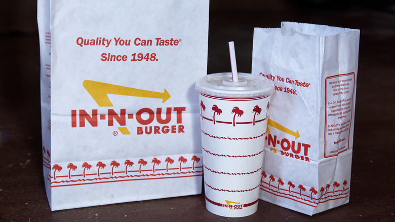 In-N-Out Burger logo paper bags and white cup with palm tree design
