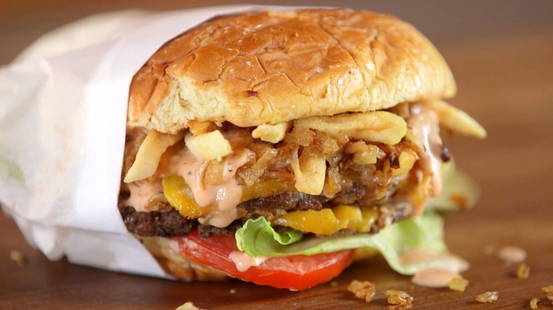 In-N-Out cheeseburger in paper sleeve with animal style fries inside