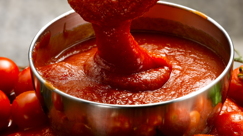 pan of tomato sauce surrounded by fresh tomatoes