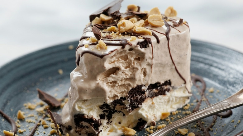 A slice of a peanut butter and whipped cream icebox cake topped with chocolate syrup and peanuts