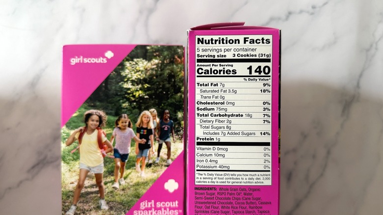 Nutrition info on box of Sparkables Girl Scout Cookie next to another cookie box on marble background