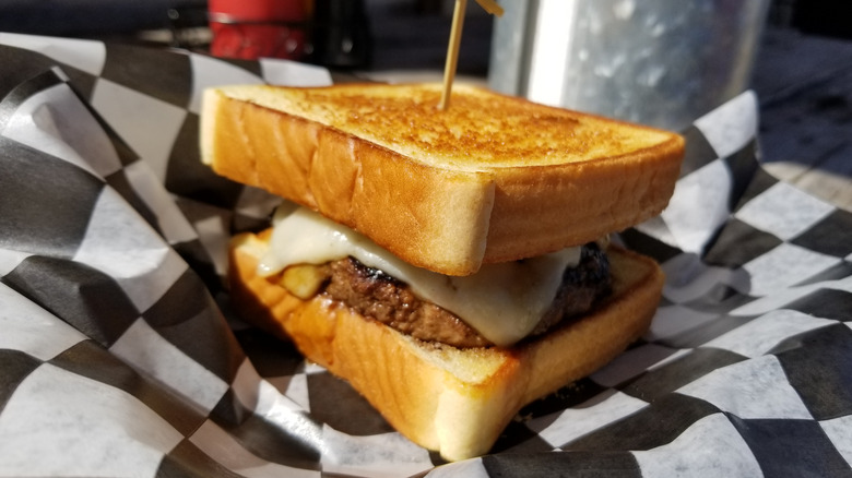 A veggie burger with melted cheese on Texas toast sitting on a piece of checkered paper