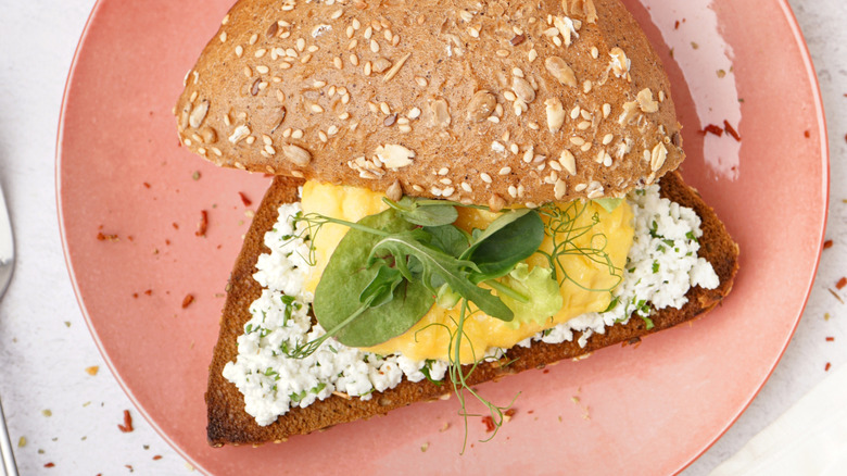 Sandwich with cottage cheese, eggs, and greens.