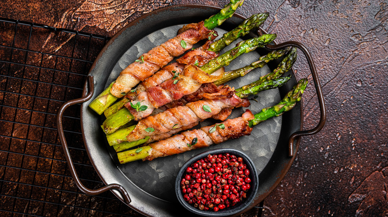 Prosciutto-wrapped asparagus and peppercorns on a tray