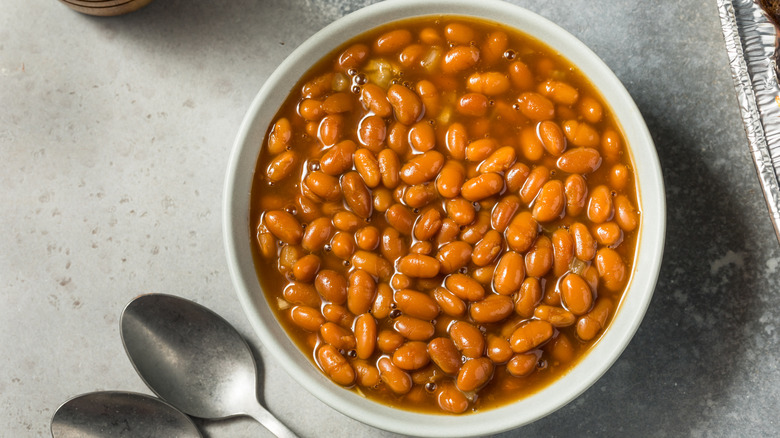 A bowl of baked beans with orange sauce