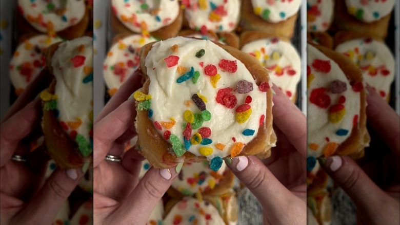Hands holding Fruity Pebbles cinnamon roll over pan