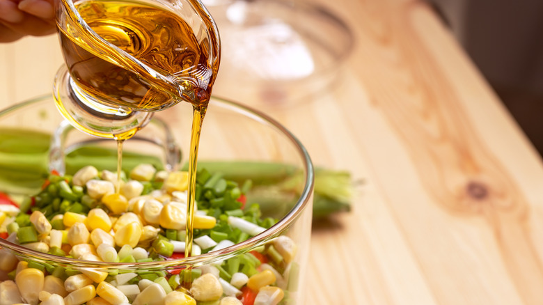 Pouring olive oil onto corn salad