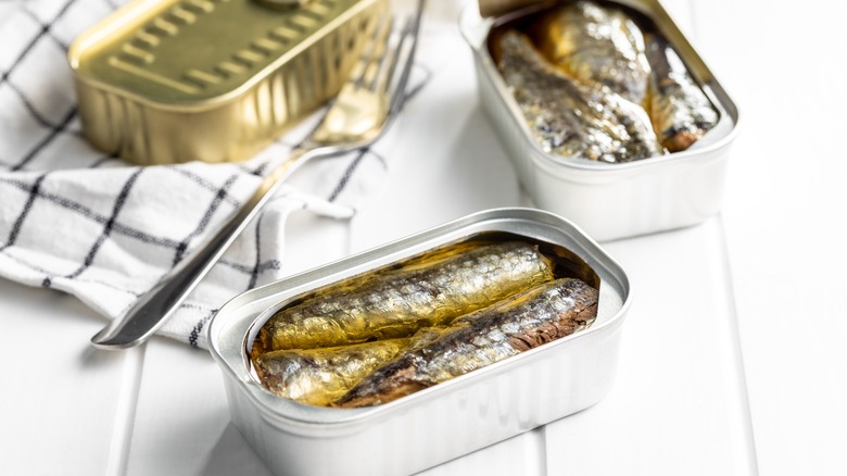 canned sardines in tins on a white wooden table